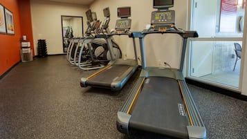 A gym with treadmills, stationary bikes, and a rowing machine.