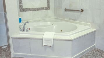 Ein Badezimmer mit einer großen Badewanne, einer Haltestange und einem Handtuch an der Seite.