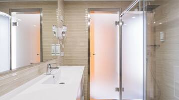 A modern bathroom with a large mirror, a sink, and a glass-enclosed shower area.