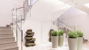 A modern interior with a staircase, white pebbles, and large planters with greenery. - Hotel Gran Sol Ibiza (Sant Antoni de Portmany)