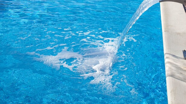 A swimming pool with clear blue water, a water fountain feature, and sun loungers in the background. - Hotel Gran Sol Ibiza (Sant Antoni de Portmany)