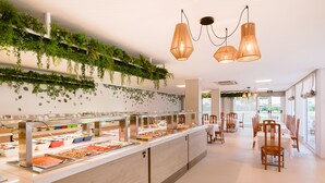 A buffet area with multiple food stations, a long counter, and hanging plants. - Hotel Gran Sol Ibiza (Sant Antoni de Portmany)