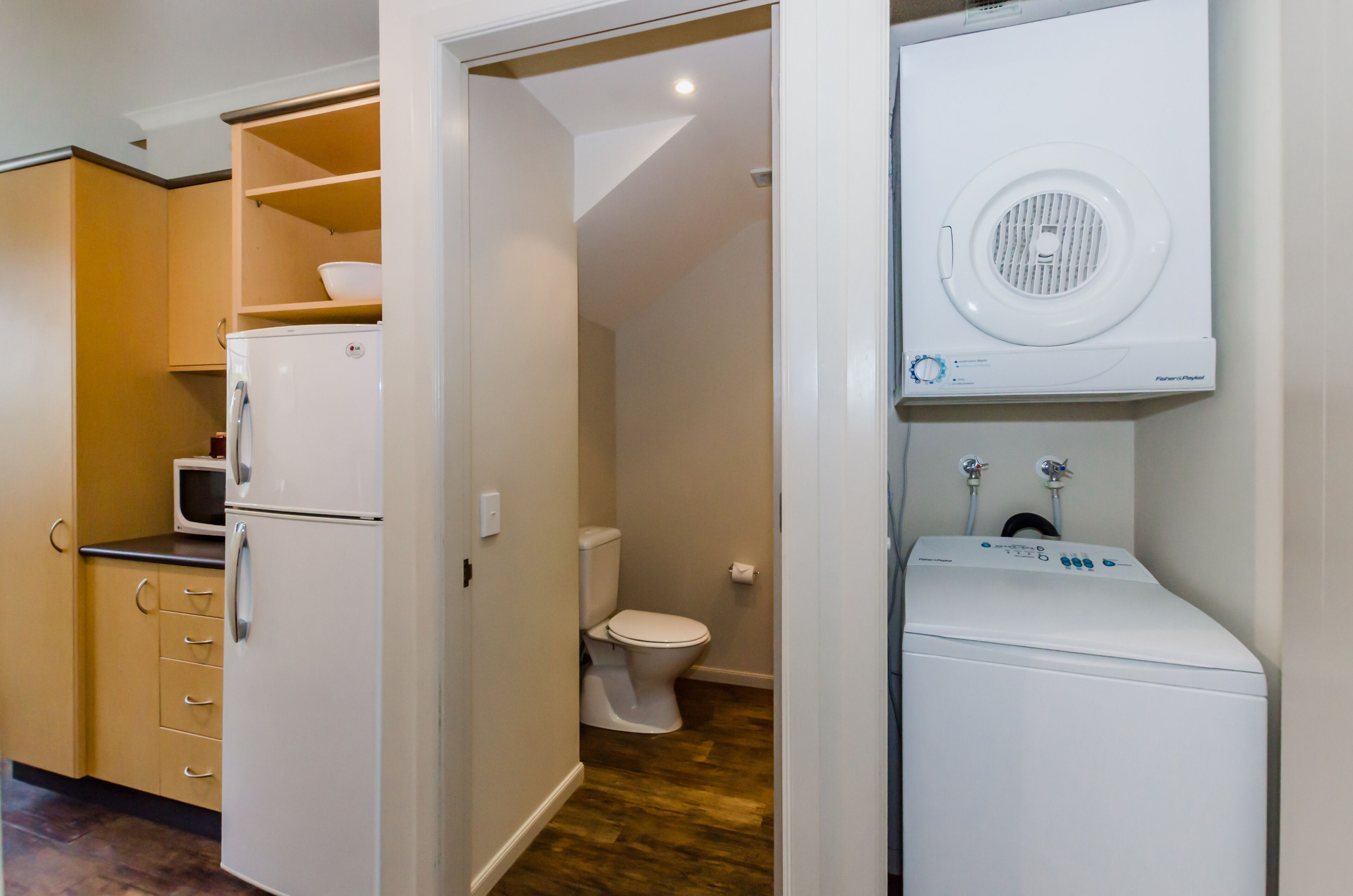 A compact kitchen with a refrigerator, microwave, and wooden cabinets.