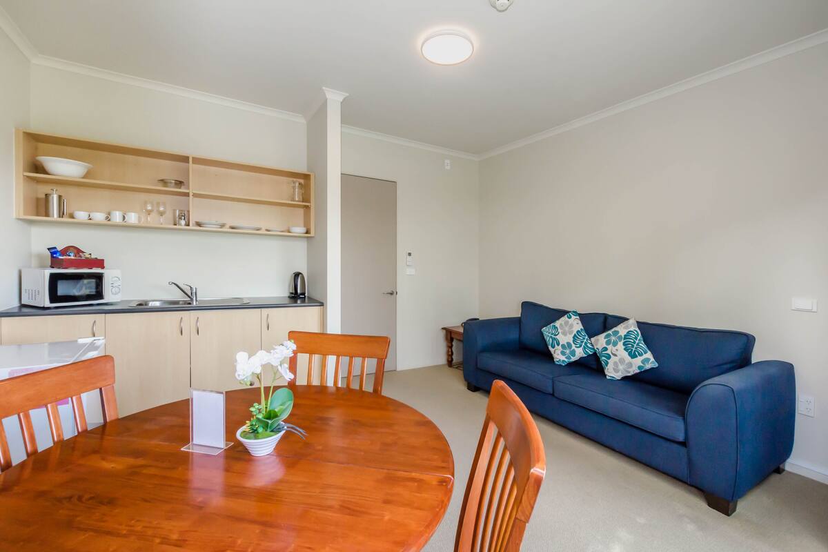 Un espacio habitable compacto con cocina, comedor y un sofá azul.