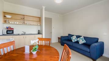 A compact living space with a kitchen, dining area, and a blue sofa.