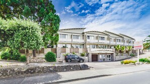 A multi-story hotel with a stone facade, balconies, and a sign for 'Raumati Sands Resort'. - Raumati Sands Resort (Paraparaumu)