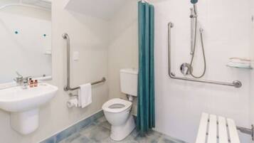 A bathroom with a white sink, toilet, and shower. There are grab bars next to the toilet and a shower curtain.