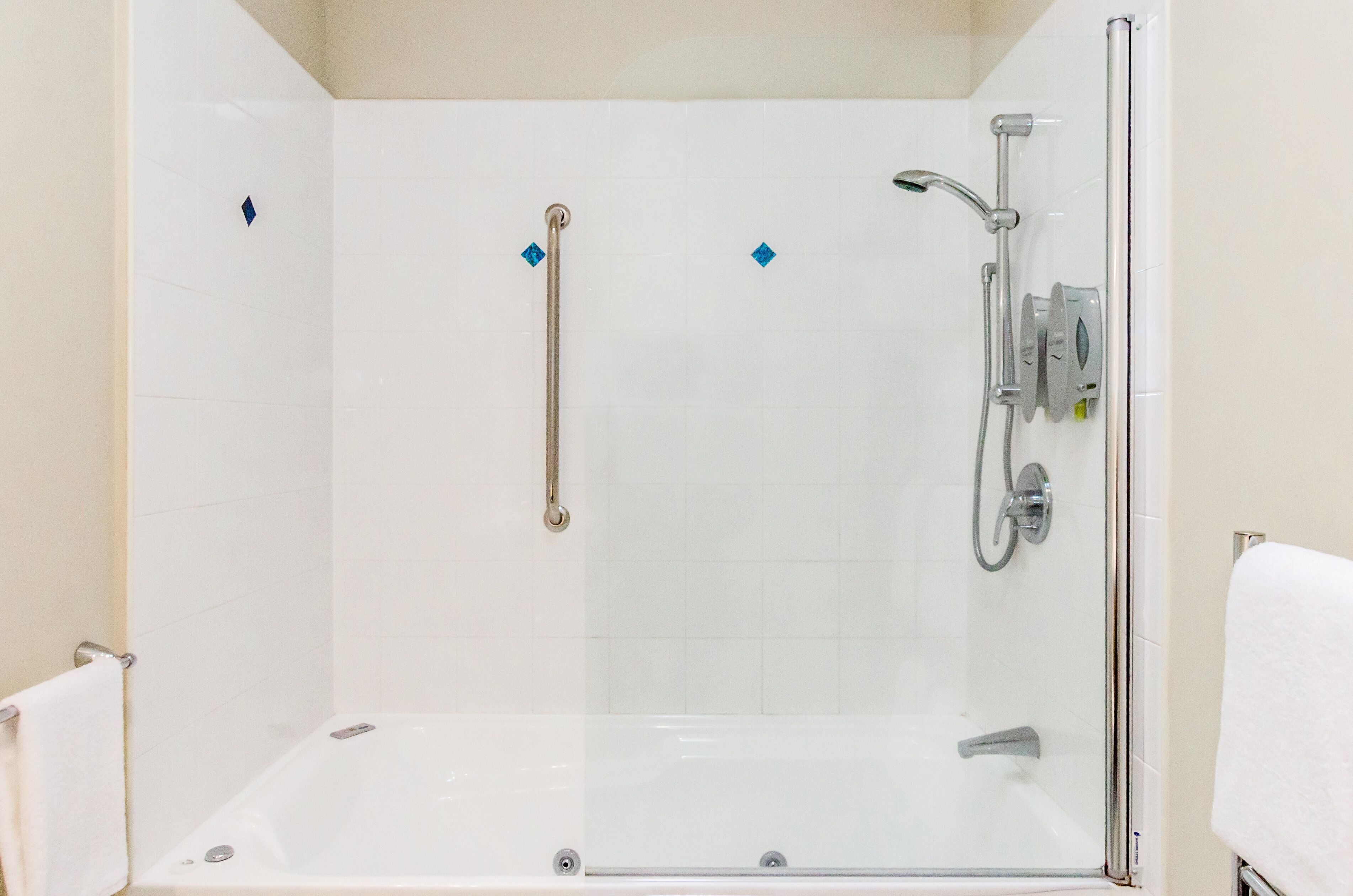 A glass-enclosed shower area with a handheld showerhead, a handheld showerhead, and a handheld showerhead.