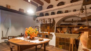Una cocina rústica con una mesa de madera, cerámica colgante y un rebozado de azulejos.