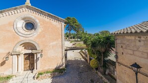 Un edificio histórico con un gran arco de entrada, una ventana circular y una cruz en la parte superior.