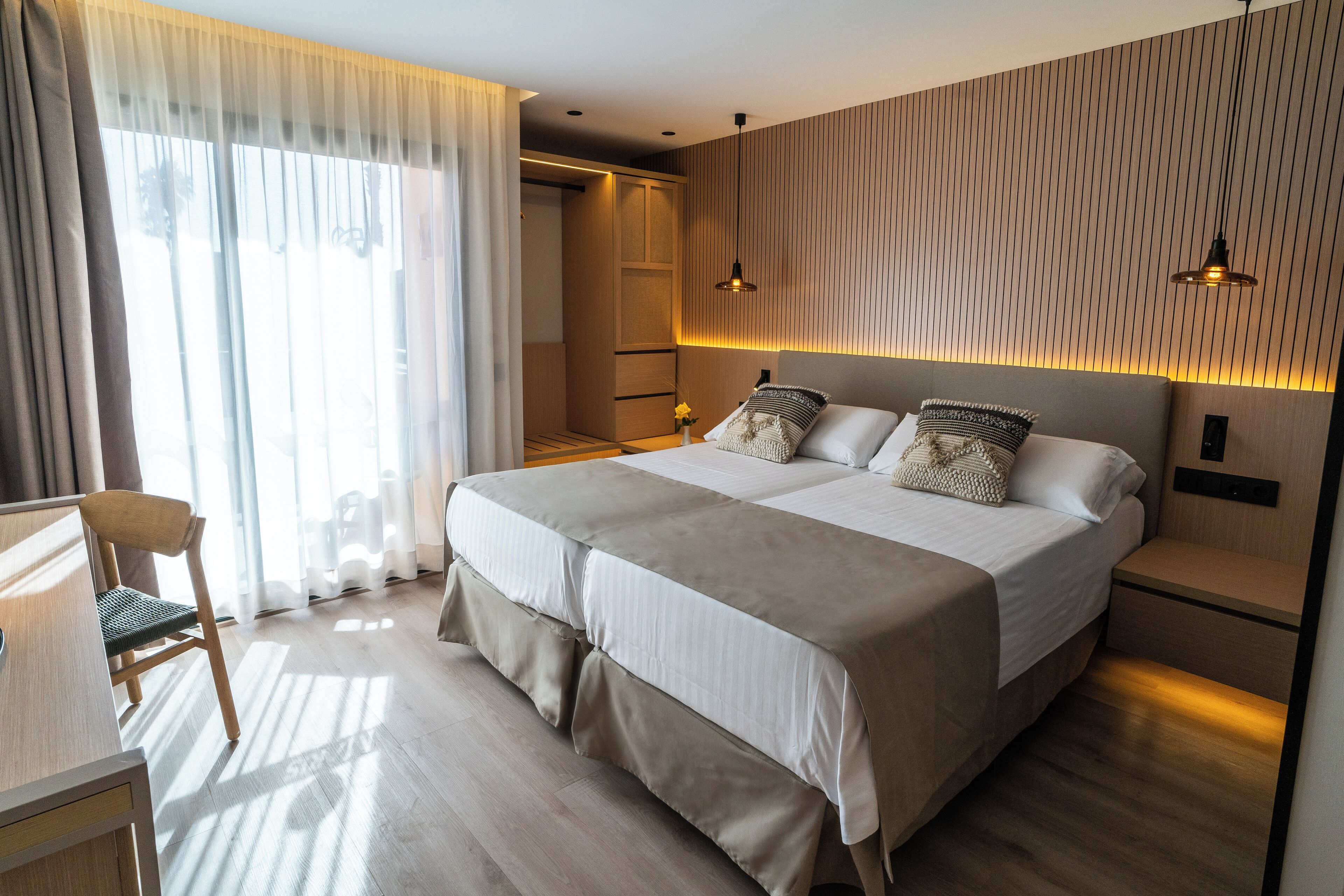 Une chambre moderne avec un grand lit, des tables de chevet, un bureau et une chaise.