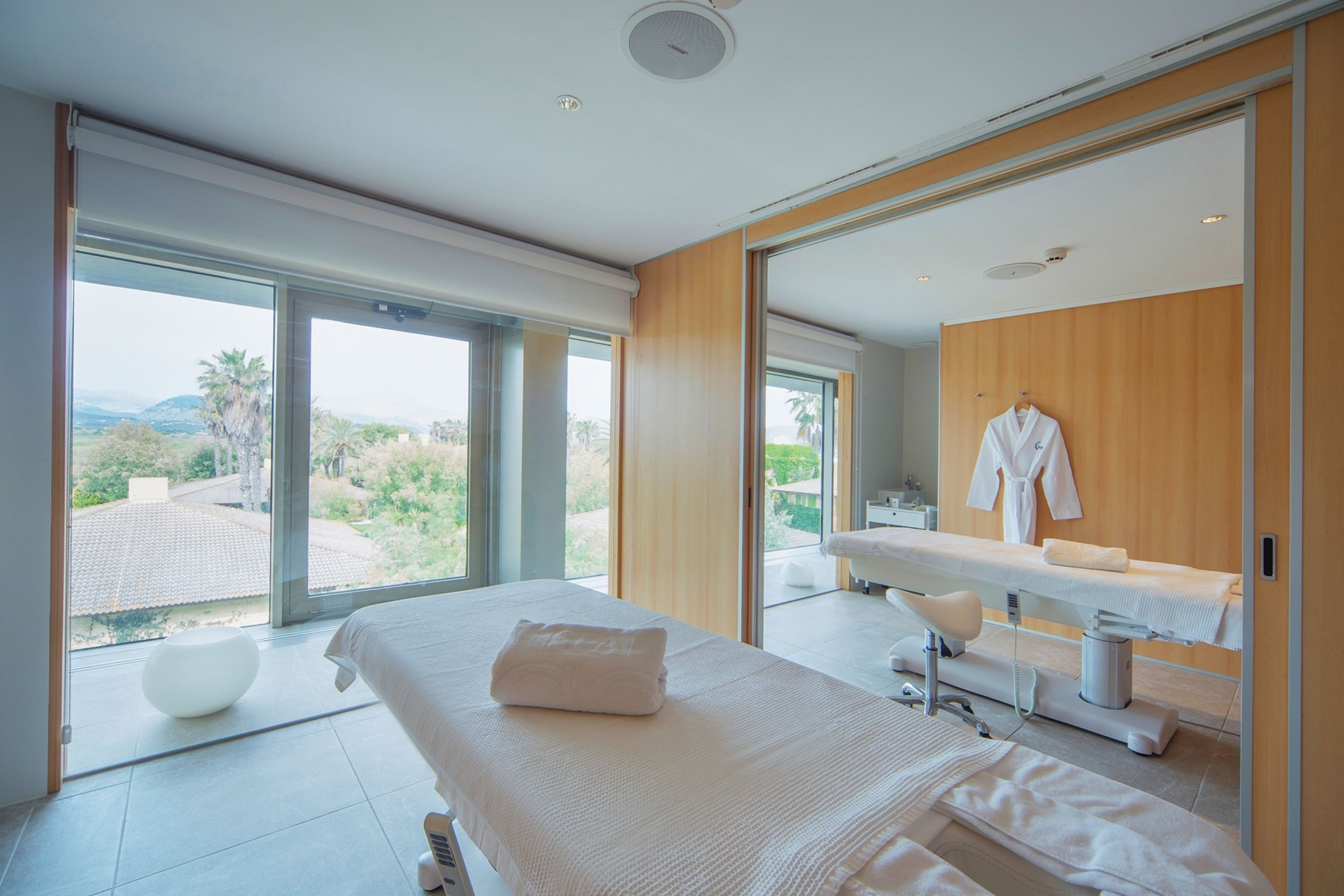 Un dormitorio moderno con una cama grande, un tocador con espejo y vistas al exterior.