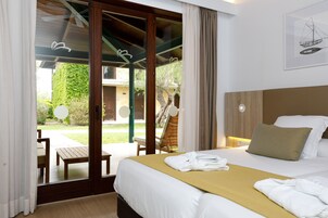 Habitación de hotel con cama, cabecero de madera, ventana con cortinas y vistas al exterior.