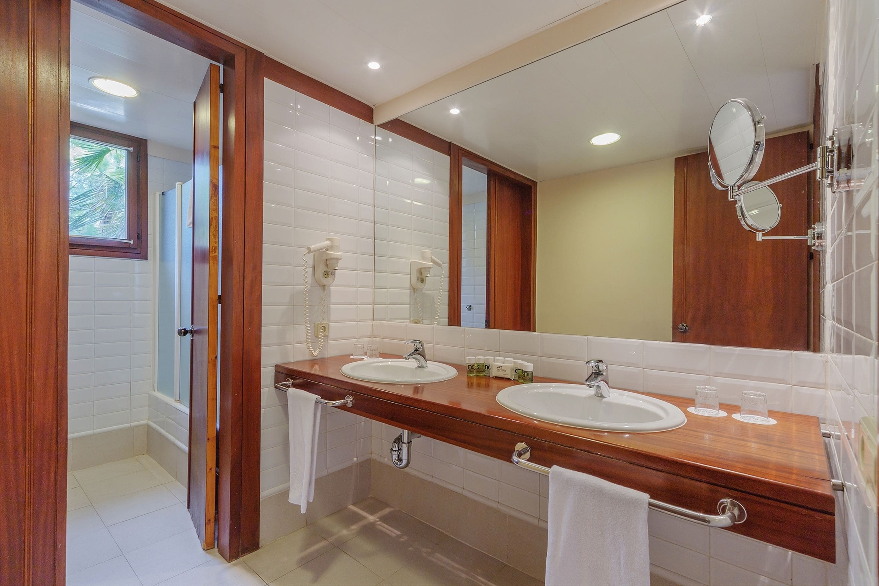 Een moderne badkamer met twee wastafels, een grote spiegel en een houten wastafelmeubel.