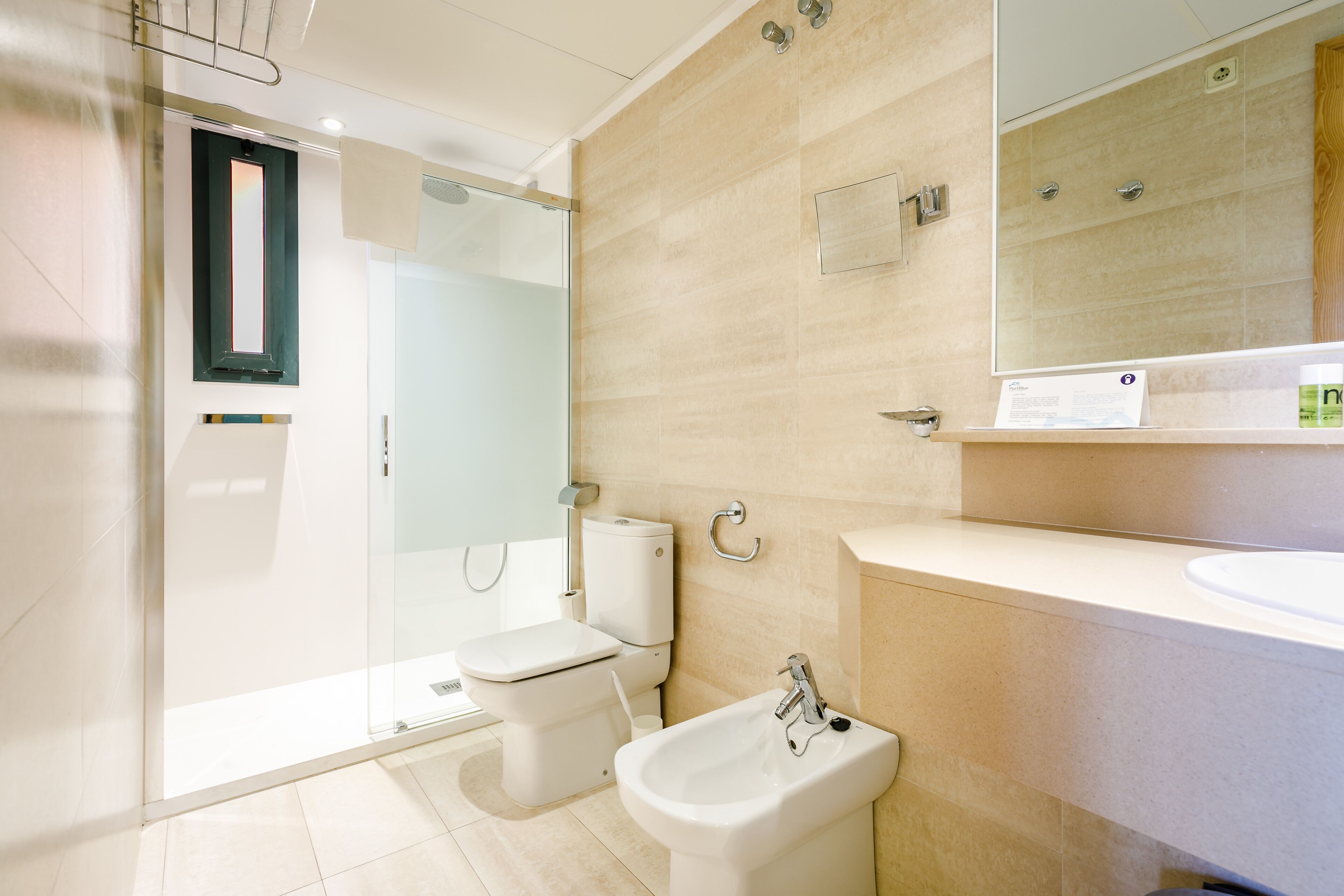 A modern bathroom with a glass shower enclosure, a toilet, a bidet, and a sink.