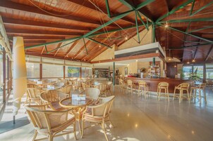 Un espacio interior amplio con techos altos, mobiliario de mimbre y una zona de bar.
