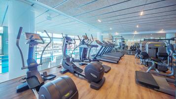 Un gimnasio con cintas de correr, elípticas y equipo de pesas.