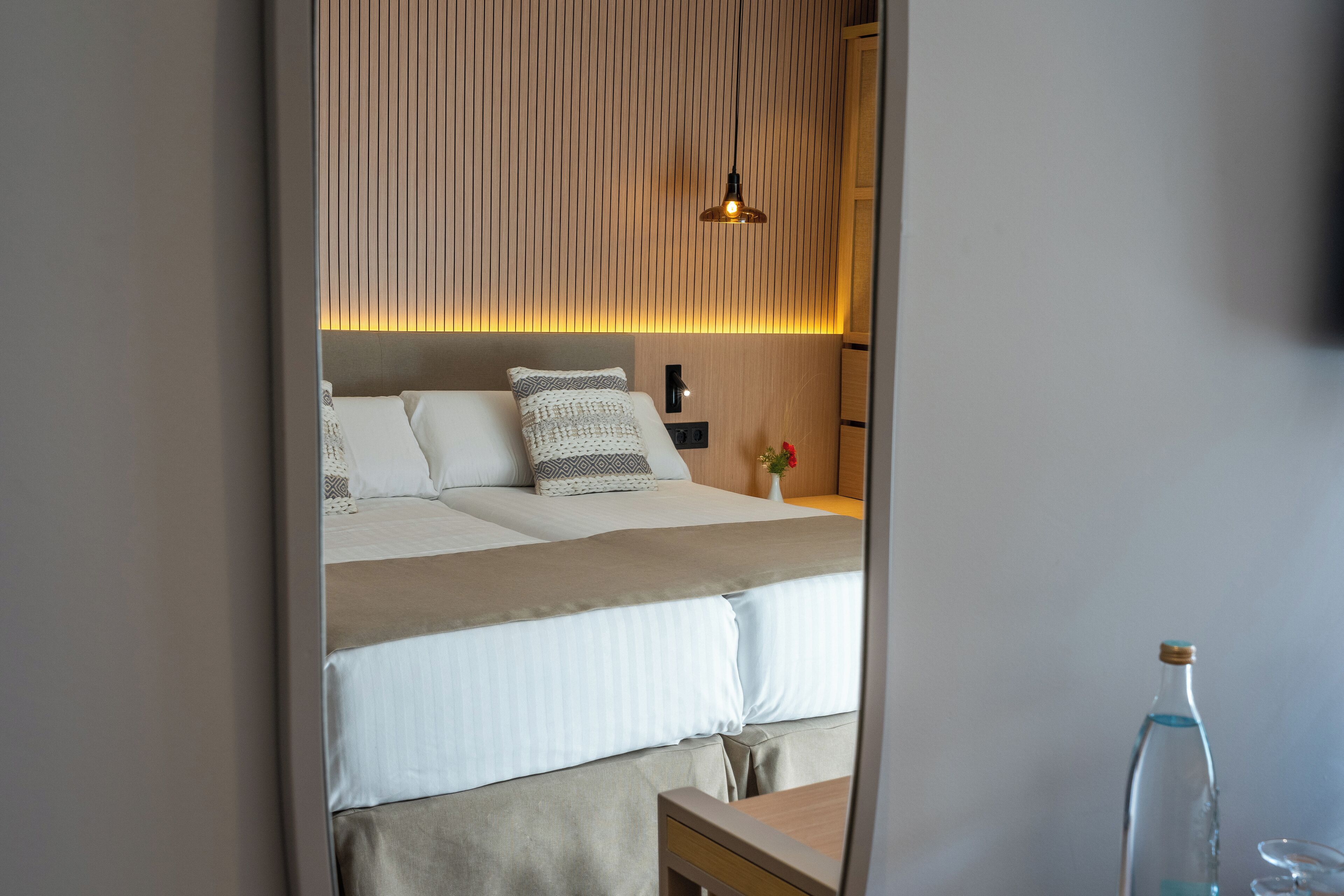 A neatly arranged hotel room with a large bed, bedside table, and a bedside lamp.