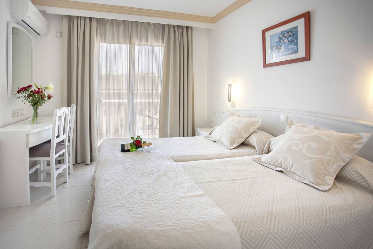 A hotel room with two beds, a desk, and a chair.