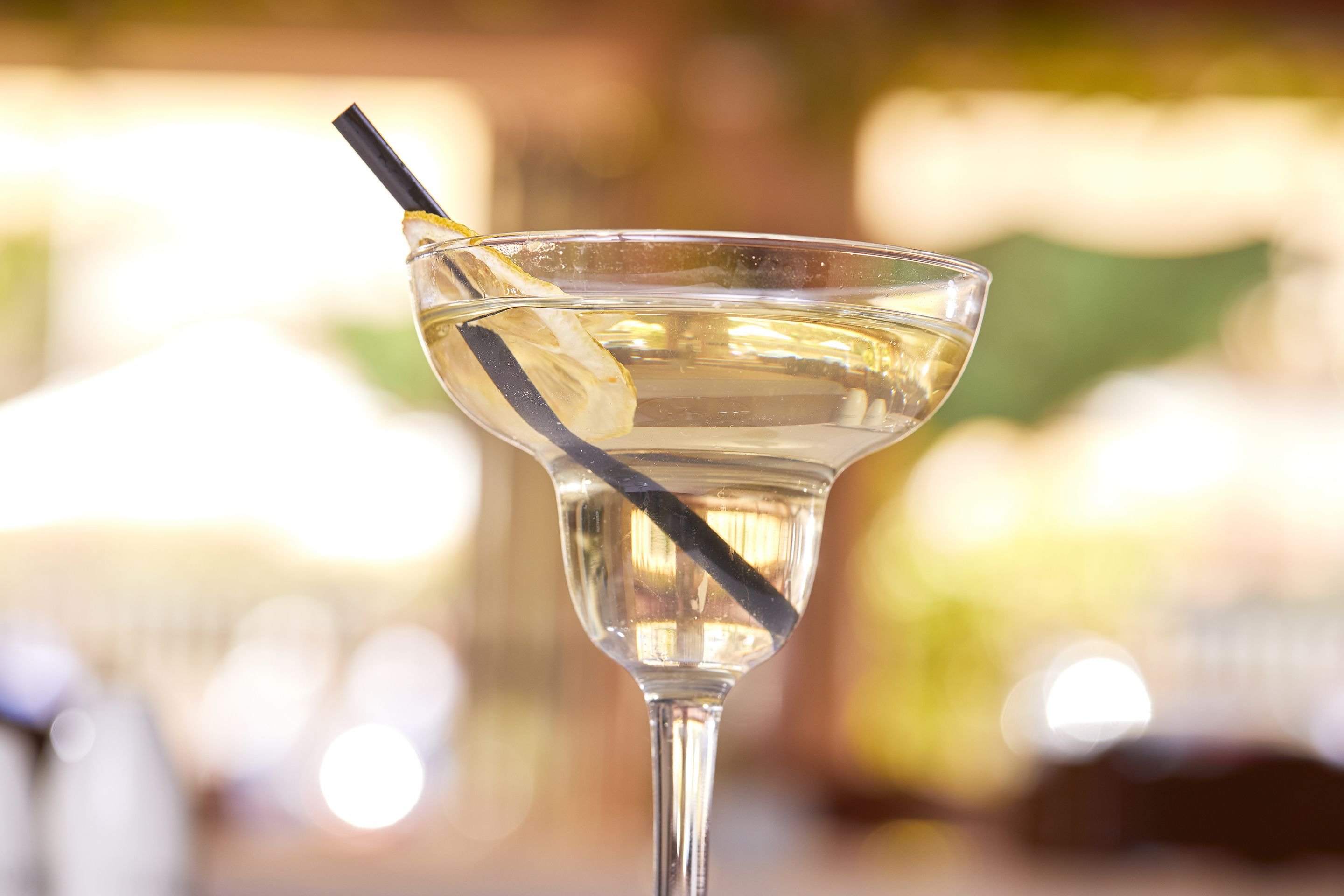 A clear glass with a straw, likely containing a beverage, with a blurred background.