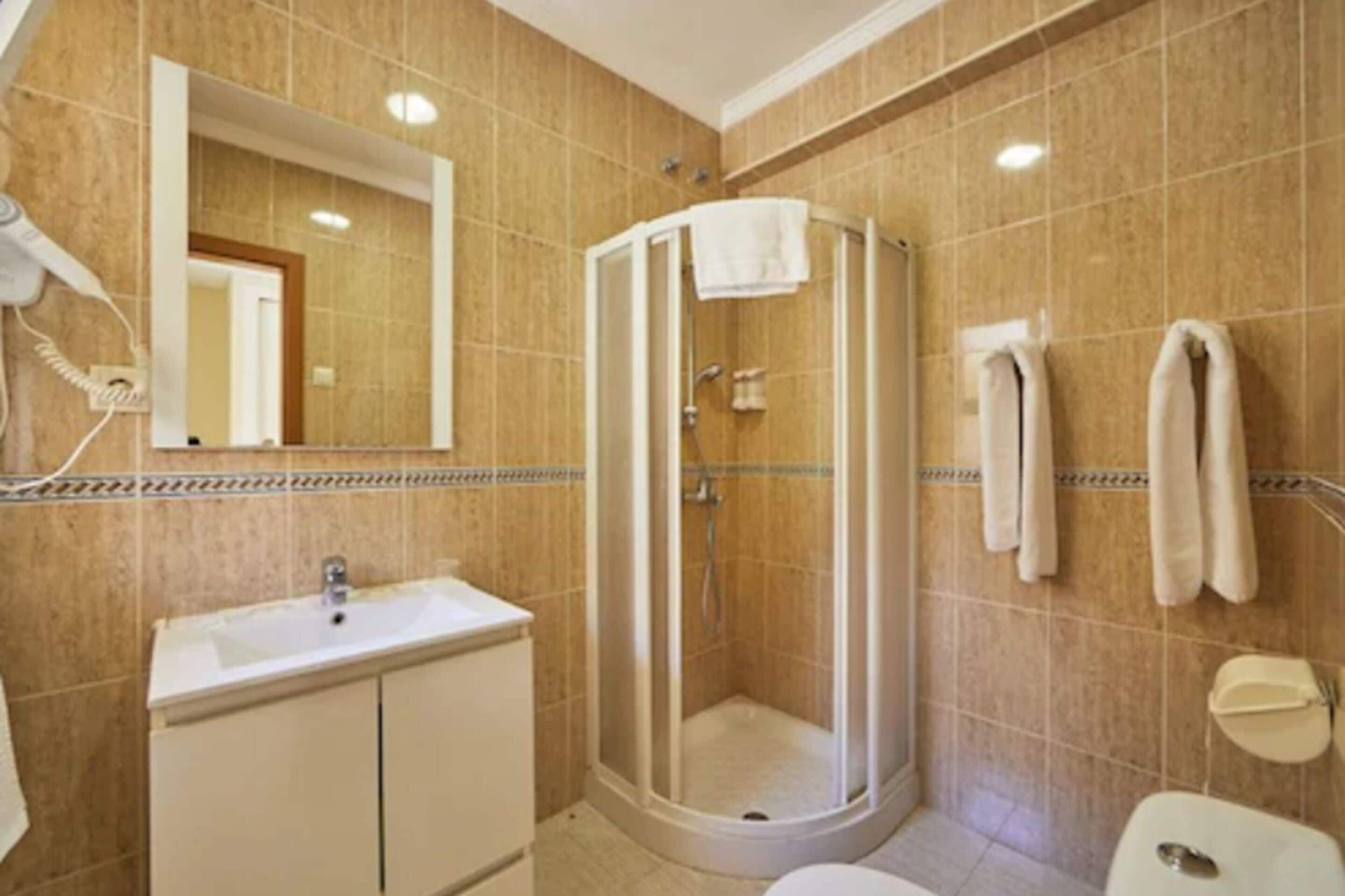 A bathroom with a shower, sink, and toilet.