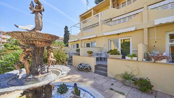 Un patio con una fuente, mobiliario exterior y un edificio con balcones.