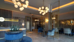 Un moderno vestíbulo de hotel con mostrador de recepción, zona de estar e iluminación decorativa.