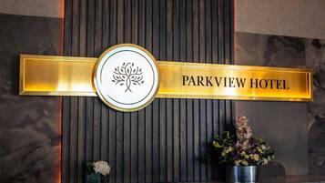 Una mesa de recepción con un cartel del Hotel Parkview, un logotipo y una planta en maceta.