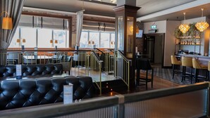 Un restaurante con asientos de cuero, una zona de bar y una escalera que conduce a un nivel superior.