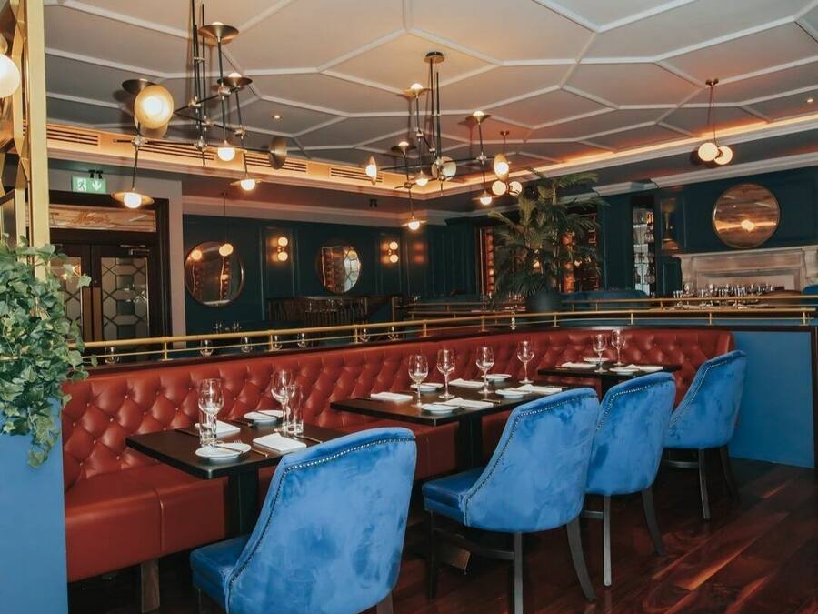 Un restaurante con techo hexagonal, cabinas rojas y sillas azules.