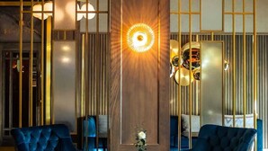 Un vestíbulo moderno con dos sillones tapizados en azul, una mesa redonda y una lámpara de pared de diseño único.