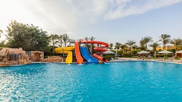 Enjoy a fun-filled day at the water park with multiple slides surrounded by lush greenery and palm trees.