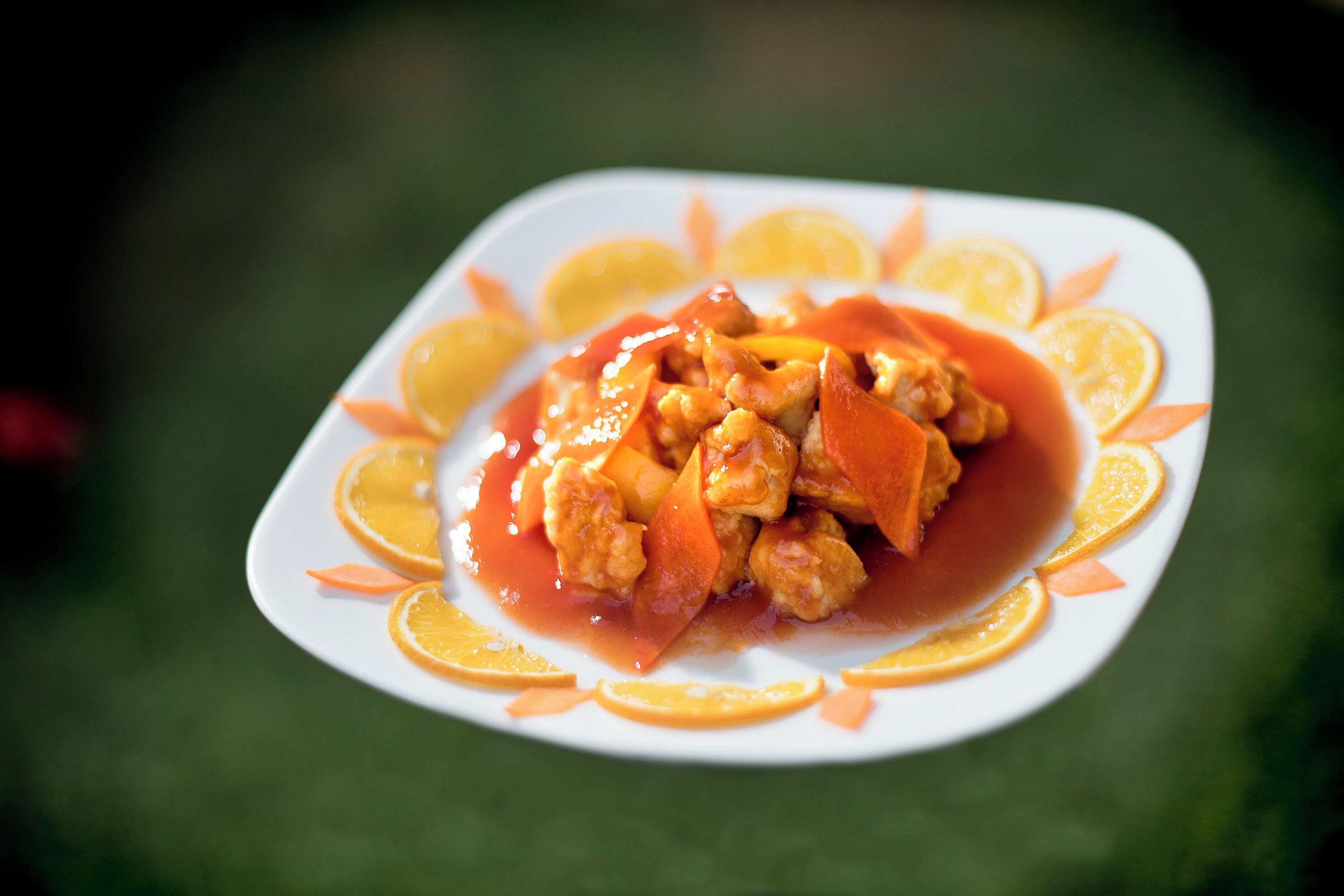 Un plato de rodajas de naranja y un recipiente con comida color naranja.