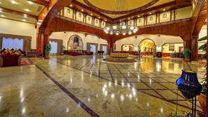 Un vestíbulo amplio con techo alto, arquitectura de madera decorada y una fuente central.