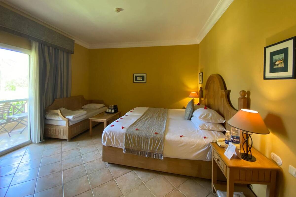 Une chambre d’hôtel avec un lit, un canapé, une petite table et une lampe.