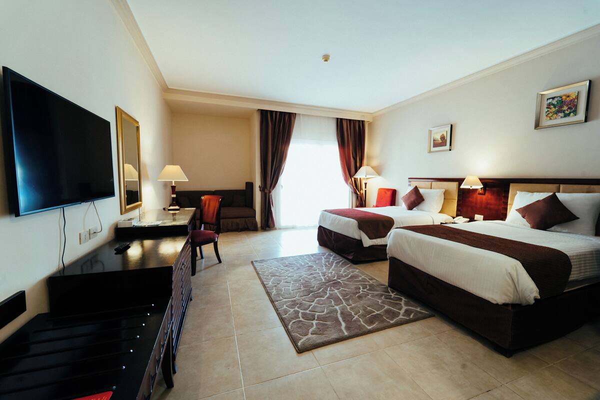 Une chambre d’hôtel avec deux lits, une télévision, un bureau et une chaise.