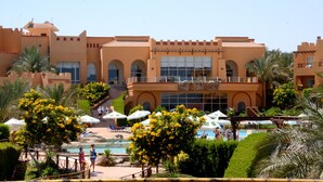 A resort with a pool area, palm trees, and a large building with arched windows and a tiled roof. - Rehana Royal Beach Resort - Aquapark & Spa - Families & Couples Only -  Premium Ultra All-Inclusive 24H (Sharm El Sheikh)