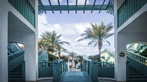 A view through a covered walkway with a staircase leading to a pool area, surrounded by palm trees and a clear sky. - Falcon Hills Hotel (Sharm El Sheikh)
