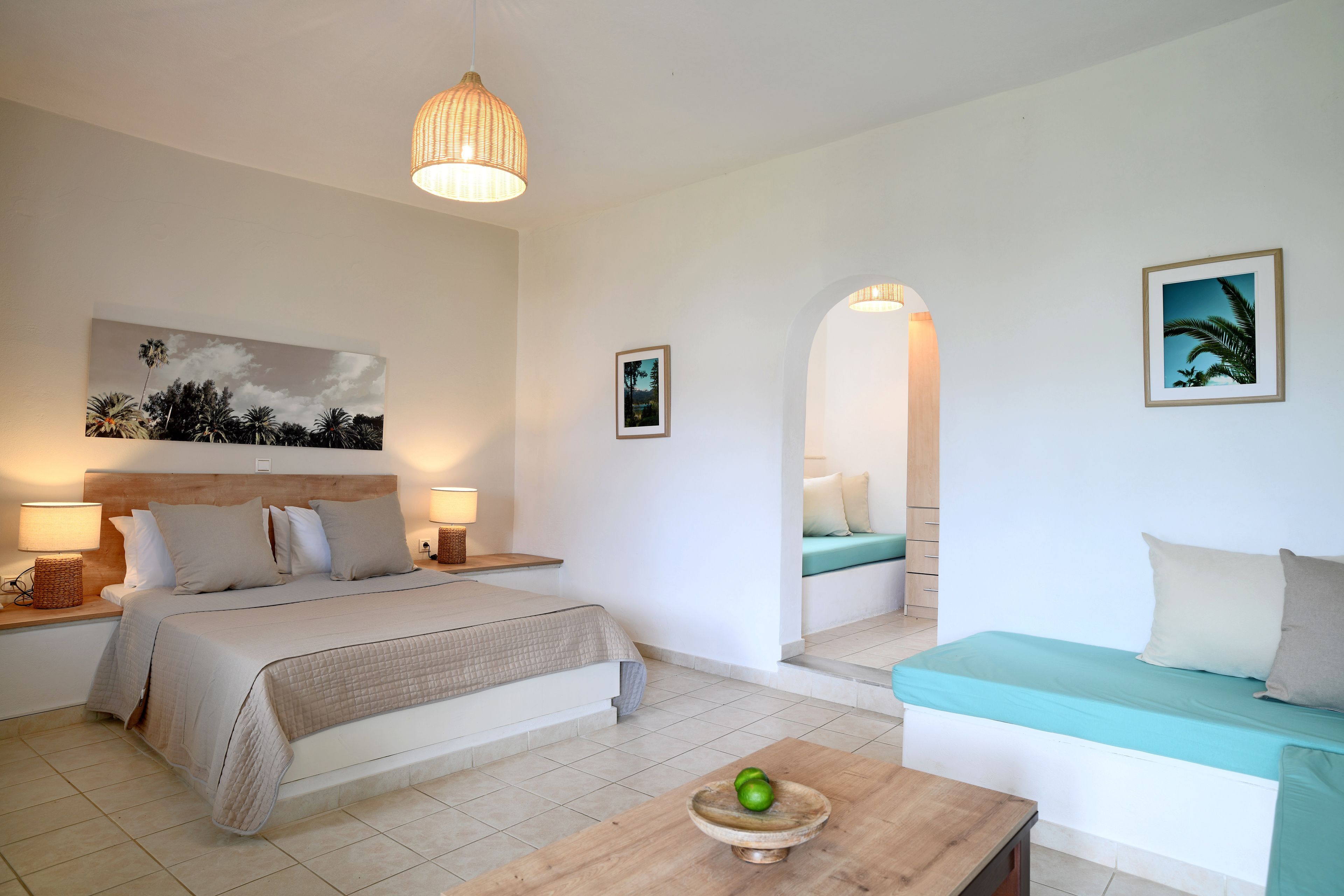Ein Schlafzimmer mit einem Bett, Nachttischen, einem Beistelltisch, einem Holztisch mit einer Schale, einer Couch und einer Wandlampe.
