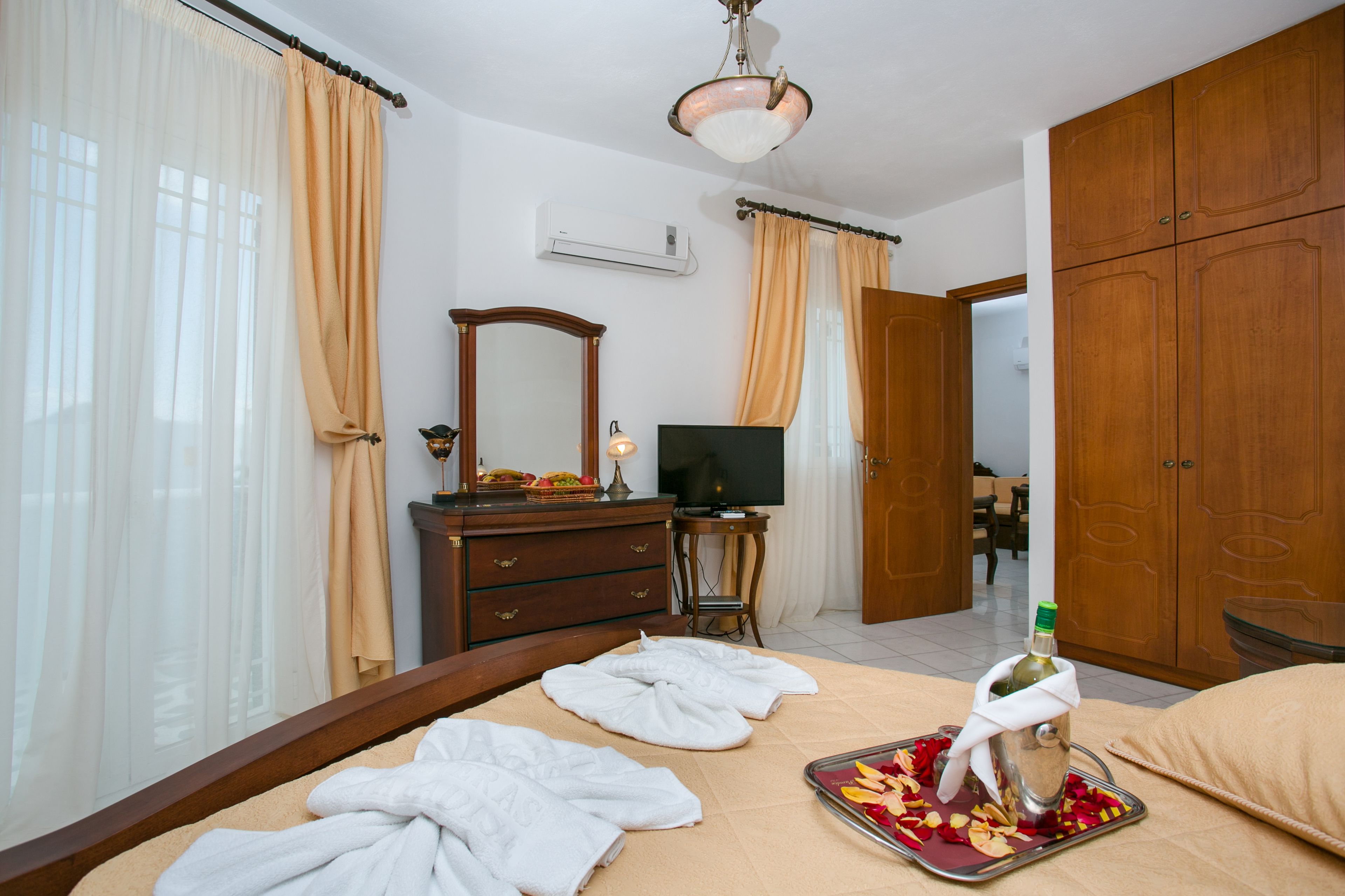 A hotel room with a bed, a TV, a dresser, and a wardrobe.