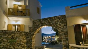 A stone archway leading to a pool area with a reception sign, suggesting a welcoming entrance to a hotel or resort.
