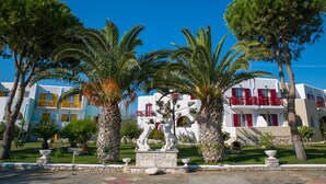 A courtyard with palm trees, a statue, and white buildings with red accents.