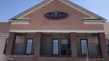 The exterior of Affordable Suites of America, featuring a prominent sign, a triangular roof, and a balcony with railings.