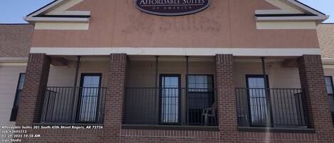 Exterior do Affordable Suites of America, com uma placa de destaque, telhado triangular e varanda com grades.