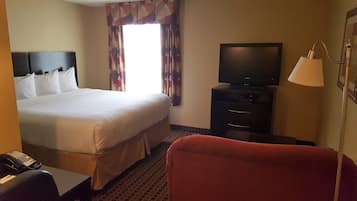 Een hotelkamer met een groot bed, een televisie, een bureau met telefoon en een rode stoel.
