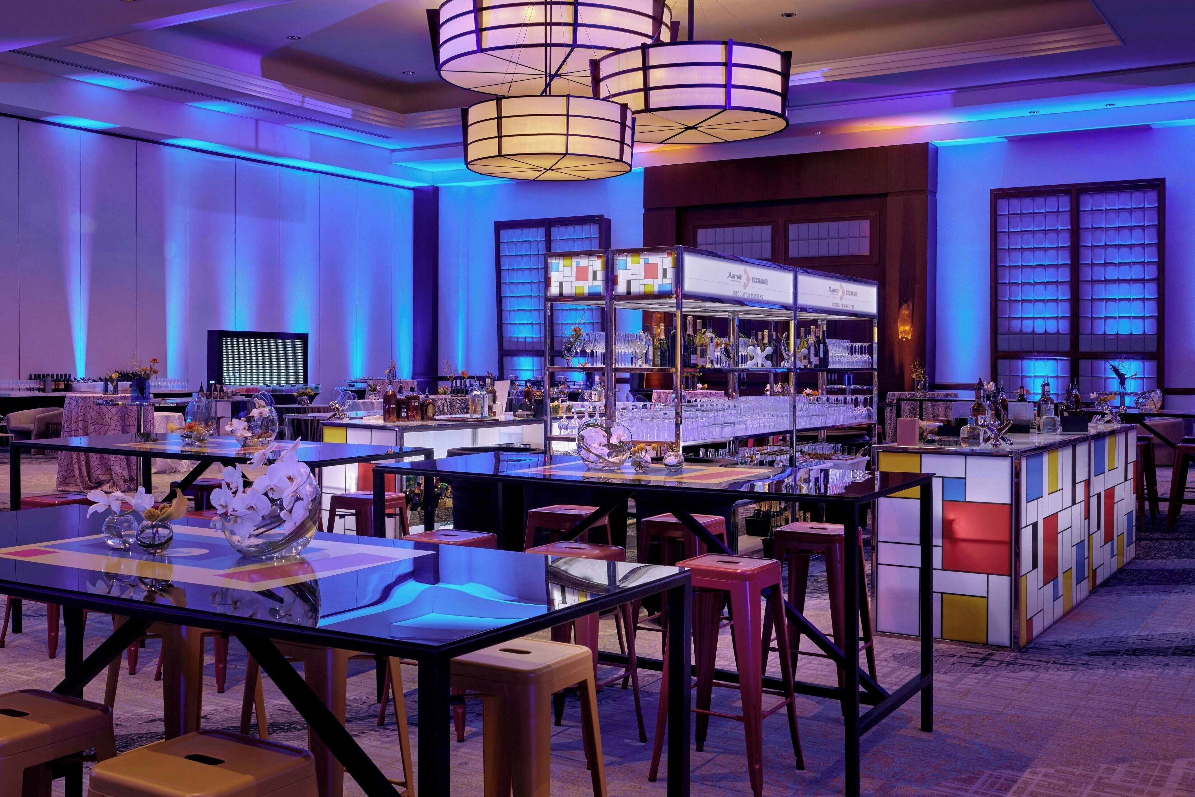 A modern hotel lobby with multiple seating areas, a bar, and a television screen.