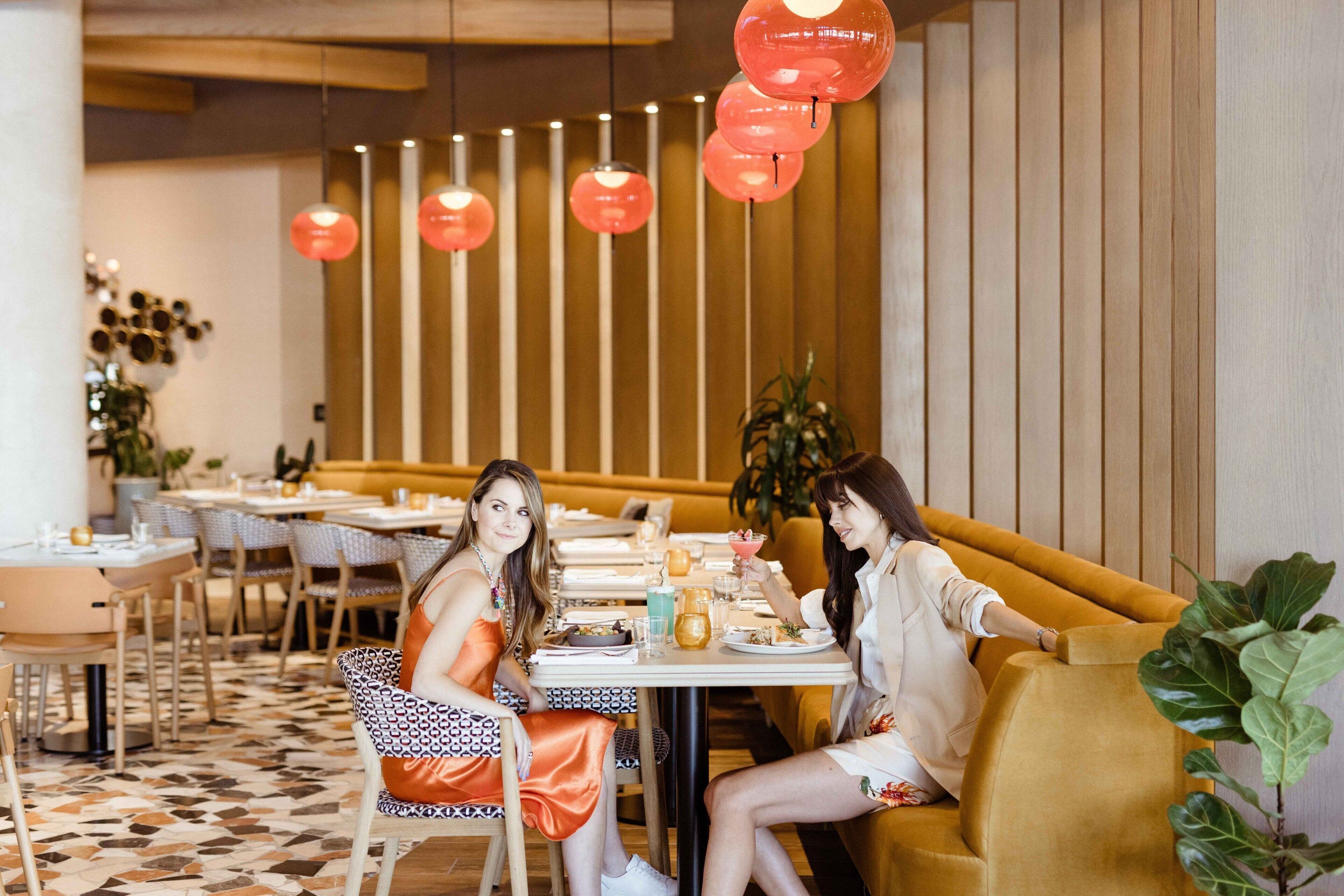 Een restaurant met een geruite vloer, houten lambrisering en rode hanglampen.