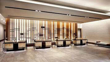 A modern lobby with a reception desk, seating area, and a decorative wall with vertical panels.