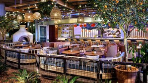 A cozy indoor seating area with tables and chairs, a fireplace, and a bar with shelves of bottles. - Sheraton Phoenix Downtown (Phoenix)