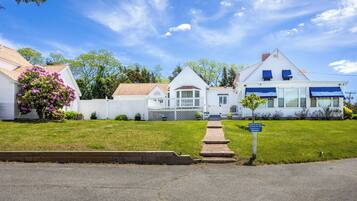 A row of white houses with a grassy lawn and a paved driveway.